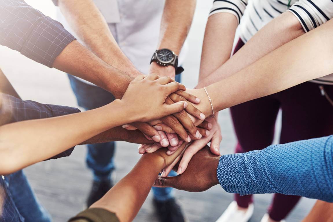 Closeup shot of a group of people joining their hands together in a huddle
