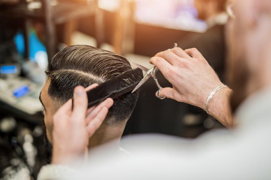 A photo of a barber's hands working at cutting somebody's hair